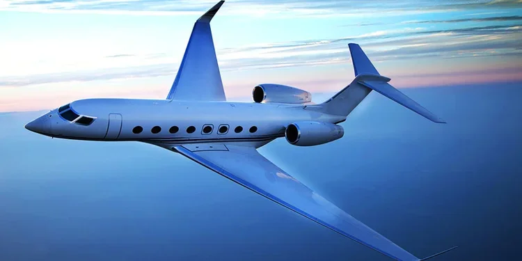 Private jet flying through the sky at sunset or sunrise with clouds in the background.