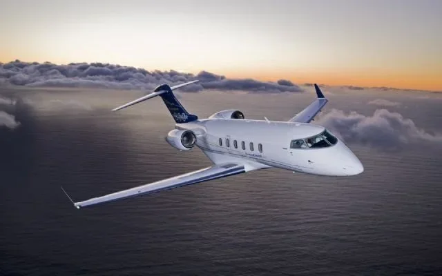 A luxury private jet flying above the clouds during sunset.