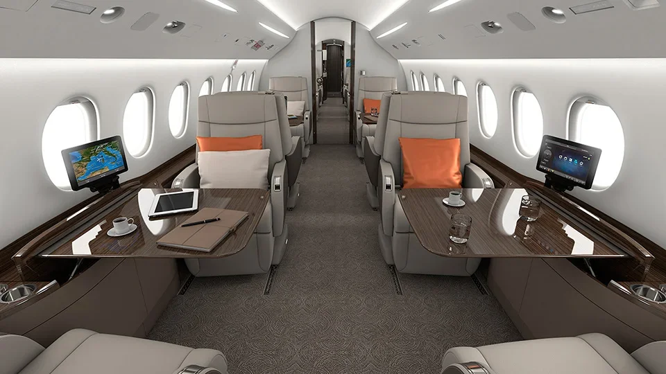 Interior of a private jet with plush seating, small tables, windows, and individual screens.