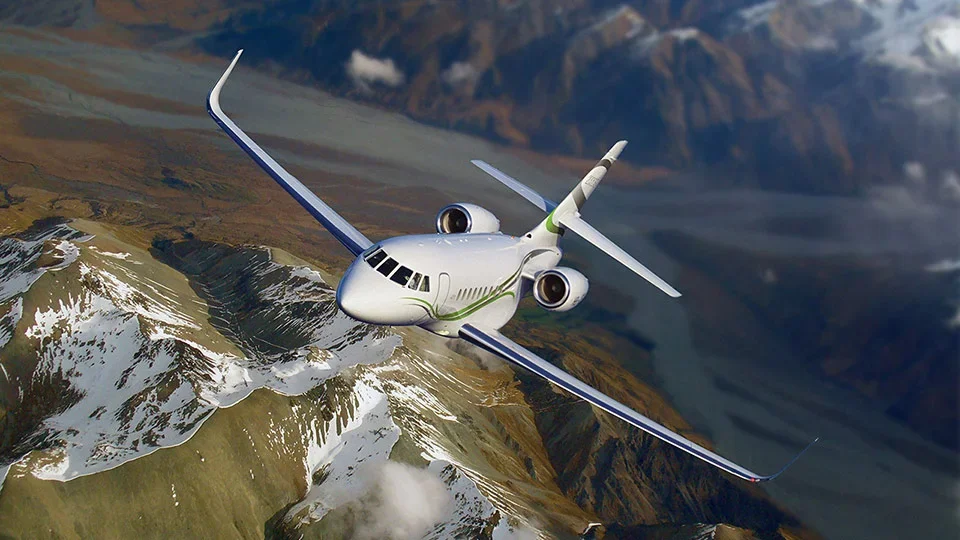 A futuristic-looking airplane flying high above snow-capped mountains.