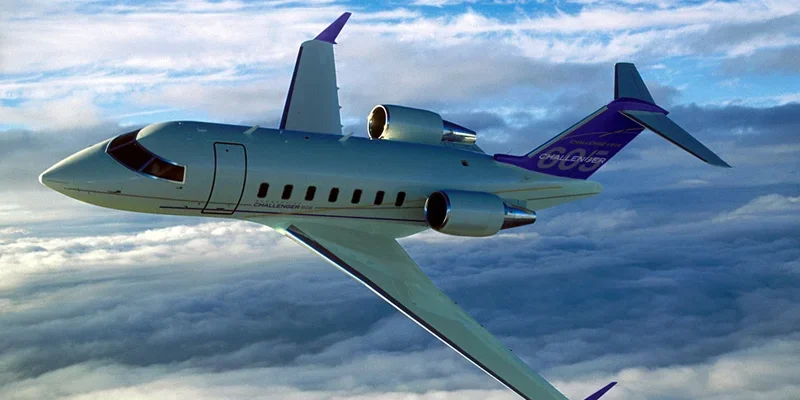 A commercial airplane flying above clouds during daytime with a blue sky.