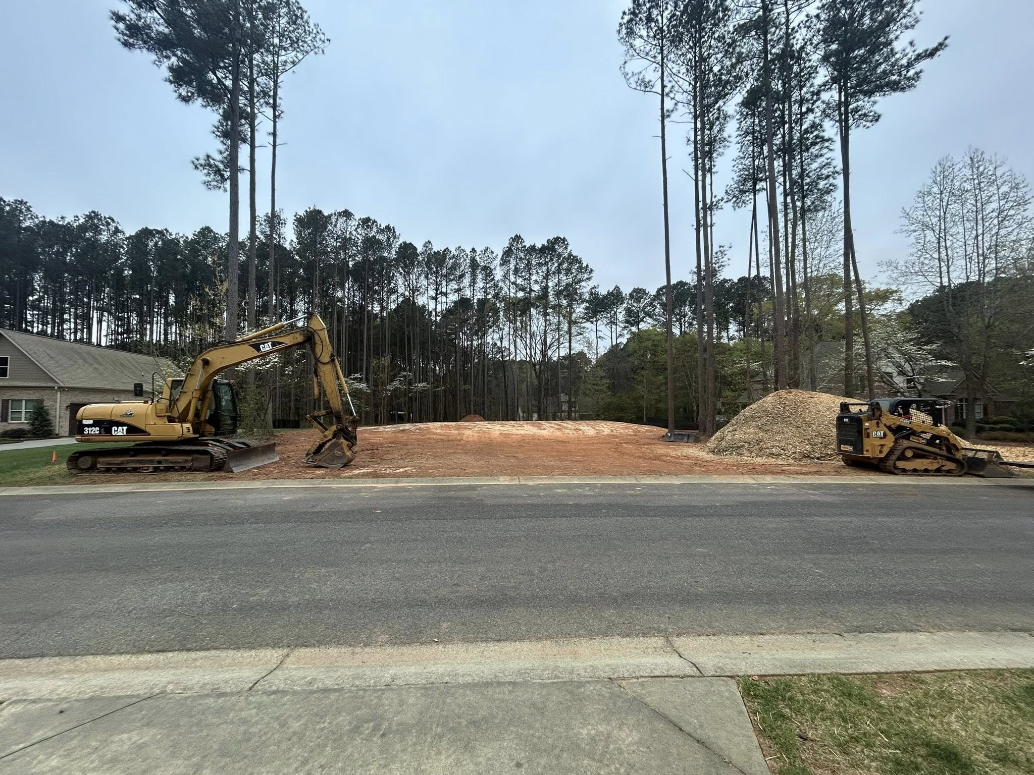 Excavator and skid steer on a cleared residential lot