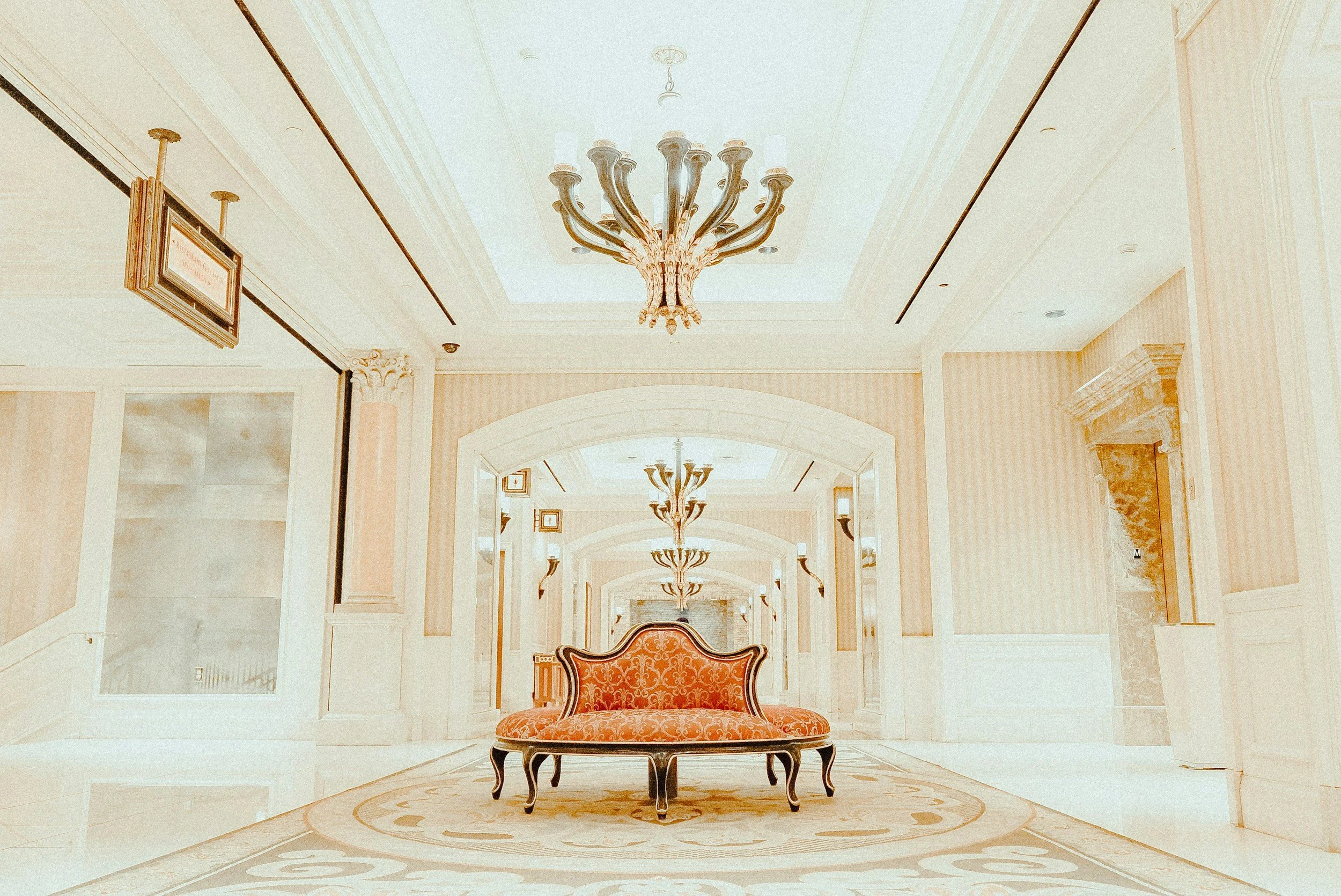 Elegantly decorated lobby of the Charleston Place hotel with a central vintage sofa, chandeliers hanging from the ceiling, and ornate moldings on the walls and columns.