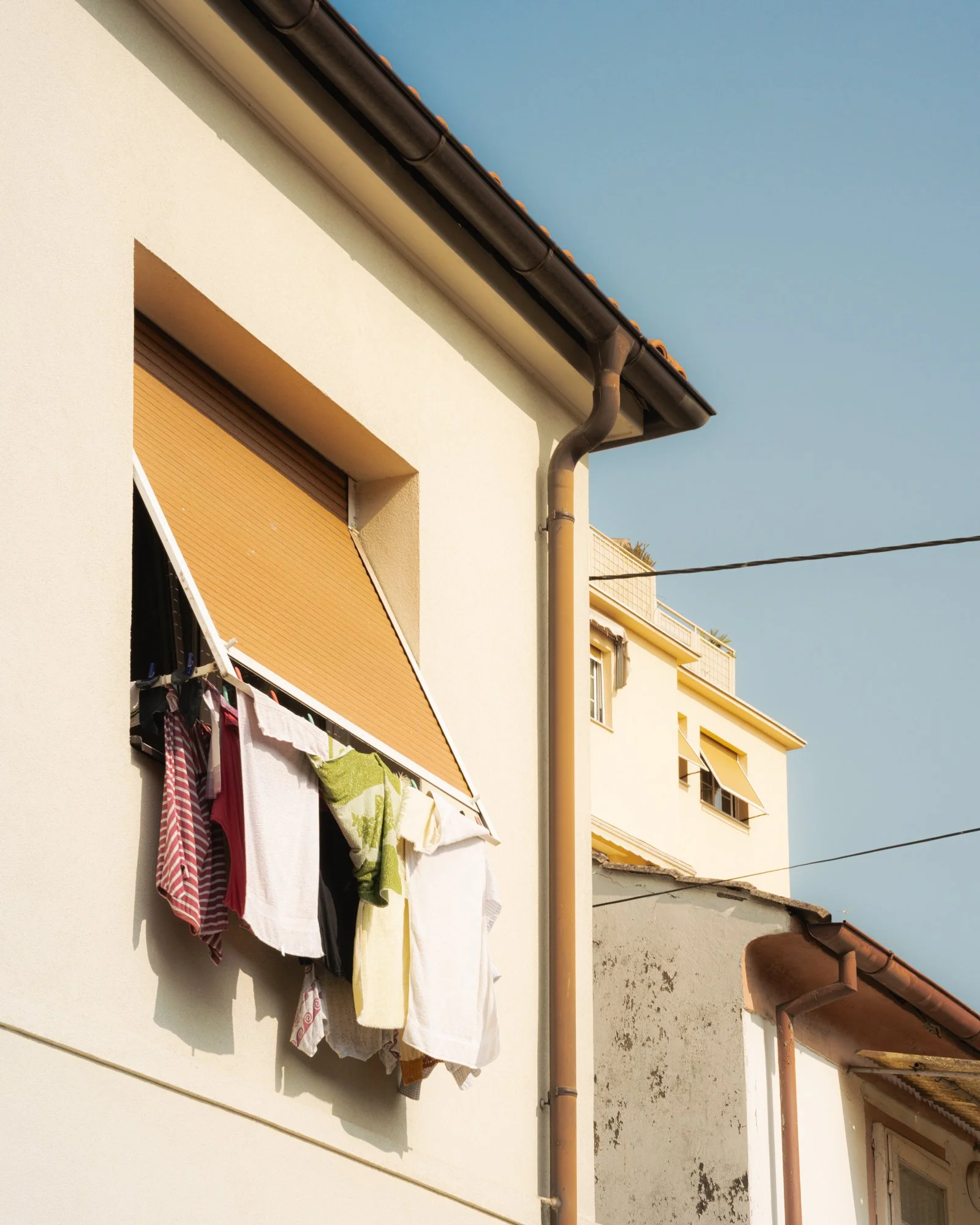 Outside view of a building with a balcony, laundry hanging, and a telephone cable in the foreground.