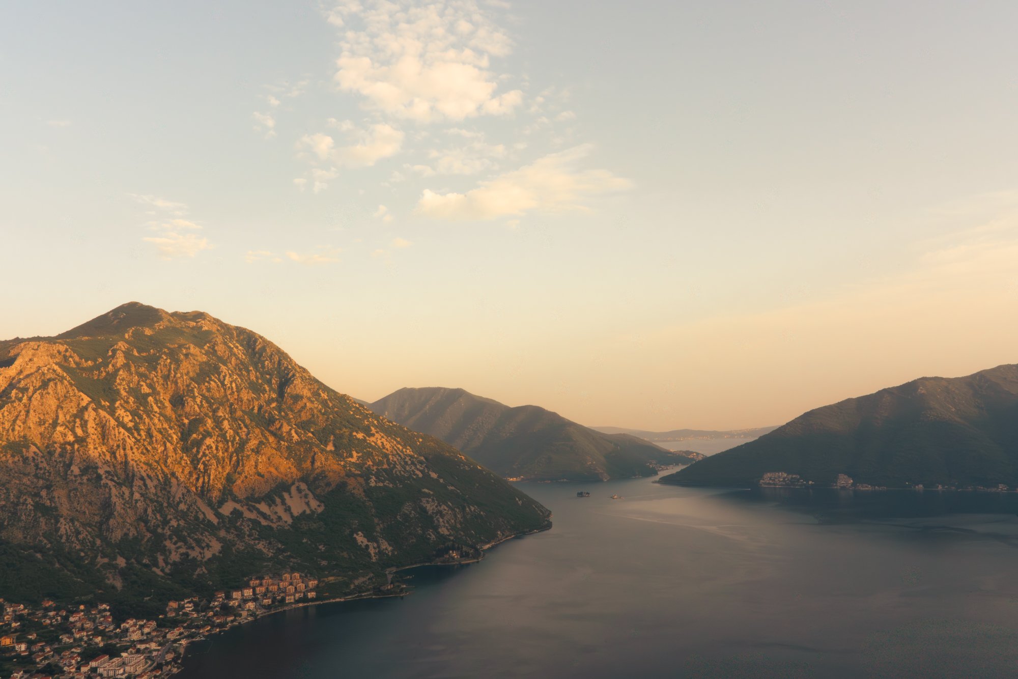 Scenic view of a river flowing through a valley with mountain ranges on either side under a partly cloudy sky.
