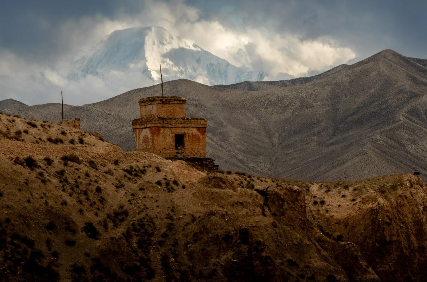 A crumbling chorten with distant Himalayan peaks in the background