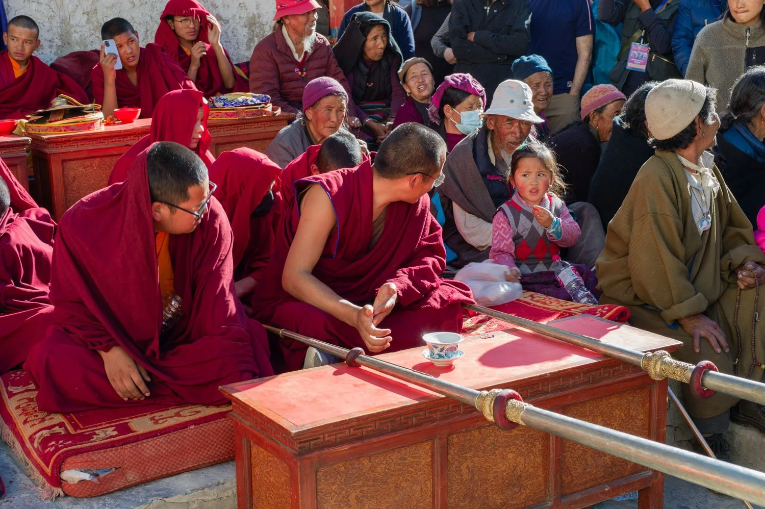 A young girl interacts with a monk at the Tiji Festival in Lo Manthang