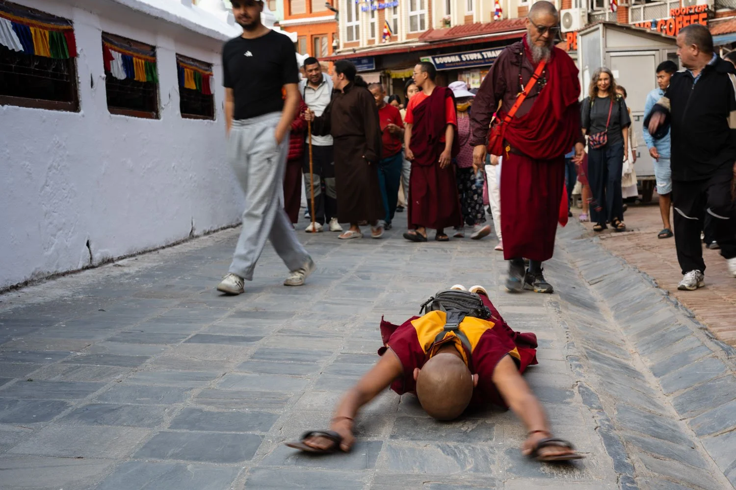 Buddhist monks prostrate before the Boudhanath stupa as they walk round the stupa