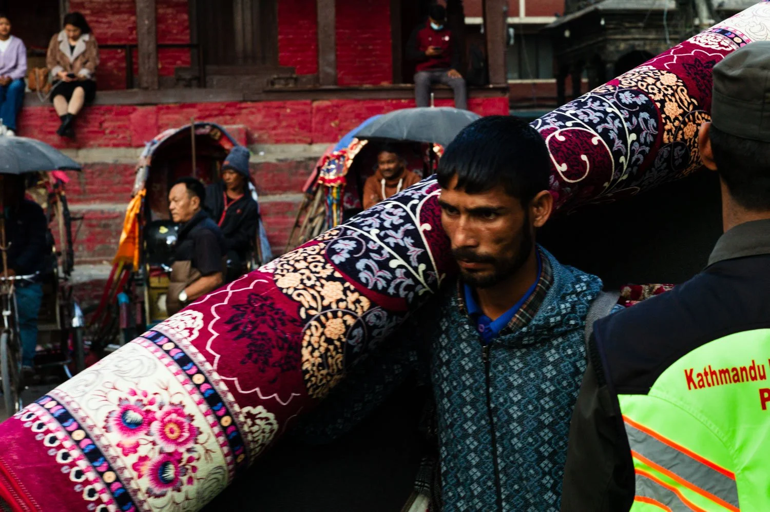 Man carrying carpet across Kathmandu's Durbar Square