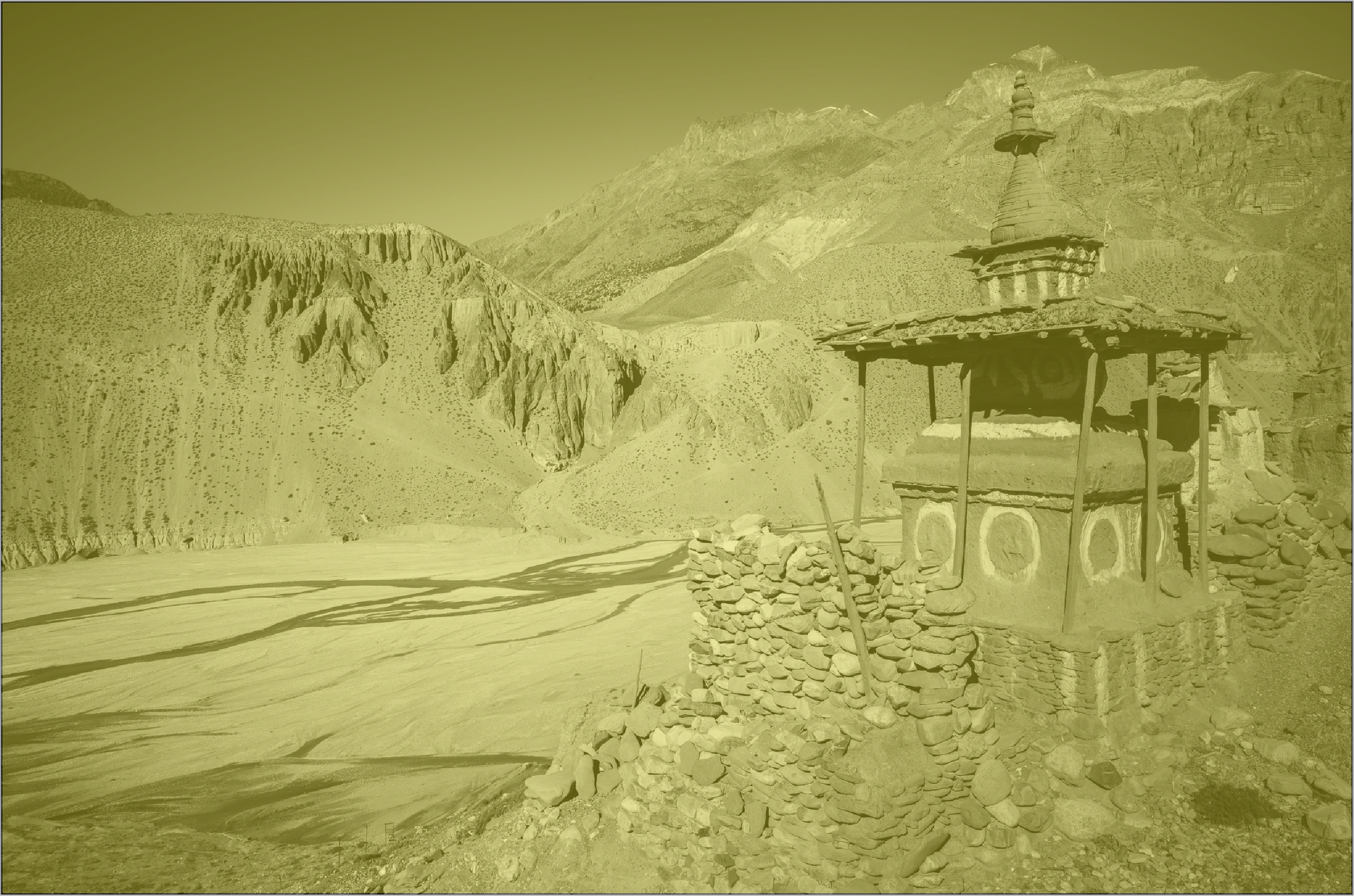 A small, traditional Buddhist temple made of stone and wood, with a tiered roof, set in a mountainous desert landscape with rugged cliffs and rocky terrain.