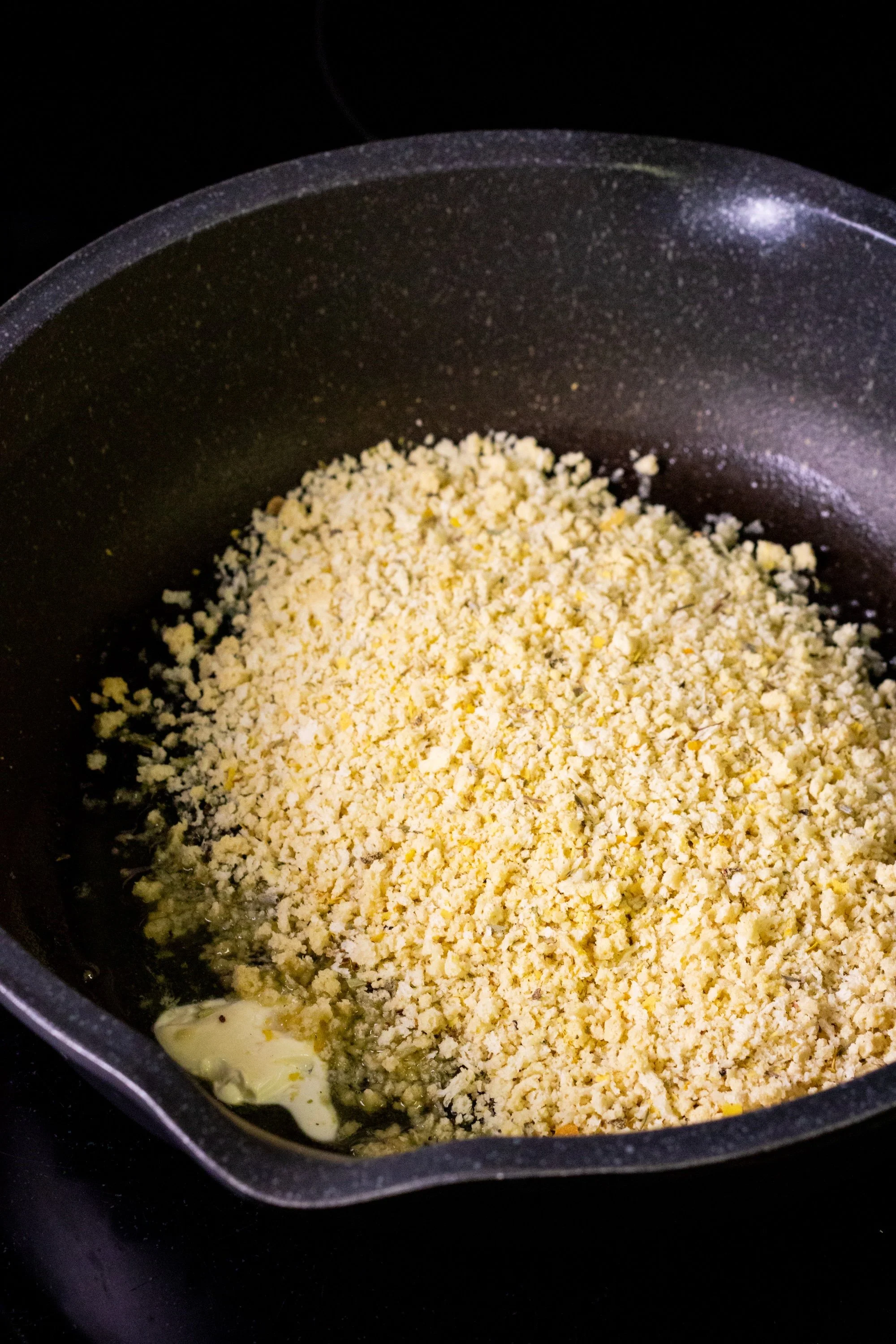 Seasoned panko breadcrumbs toasting in vegan butter in a skillet.