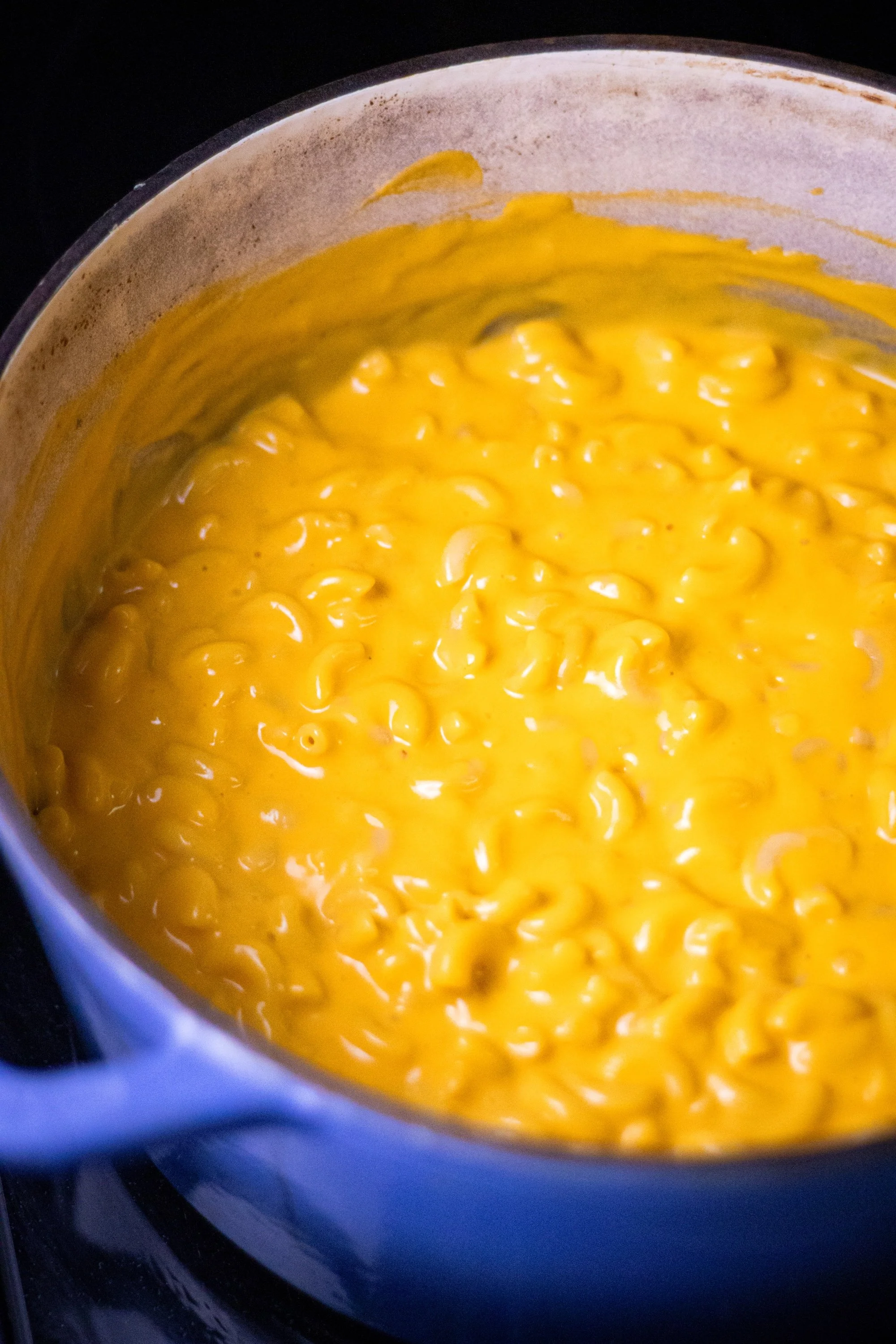 Elbow pasta coated in creamy butternut squash cheese sauce in a blue pot.