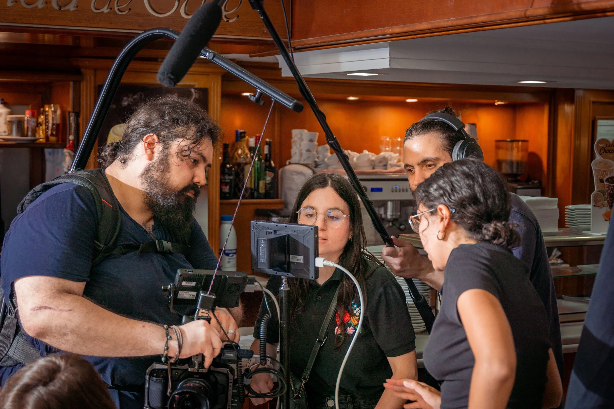 Cuatro personas revisando un monitor, con equipo de grabación y micrófono para grabar o filmar.