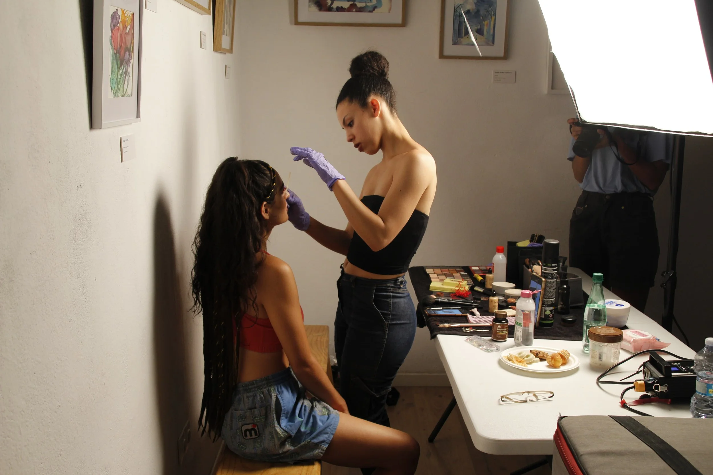 Una mujer maquilla a Camila en un espacio de interior