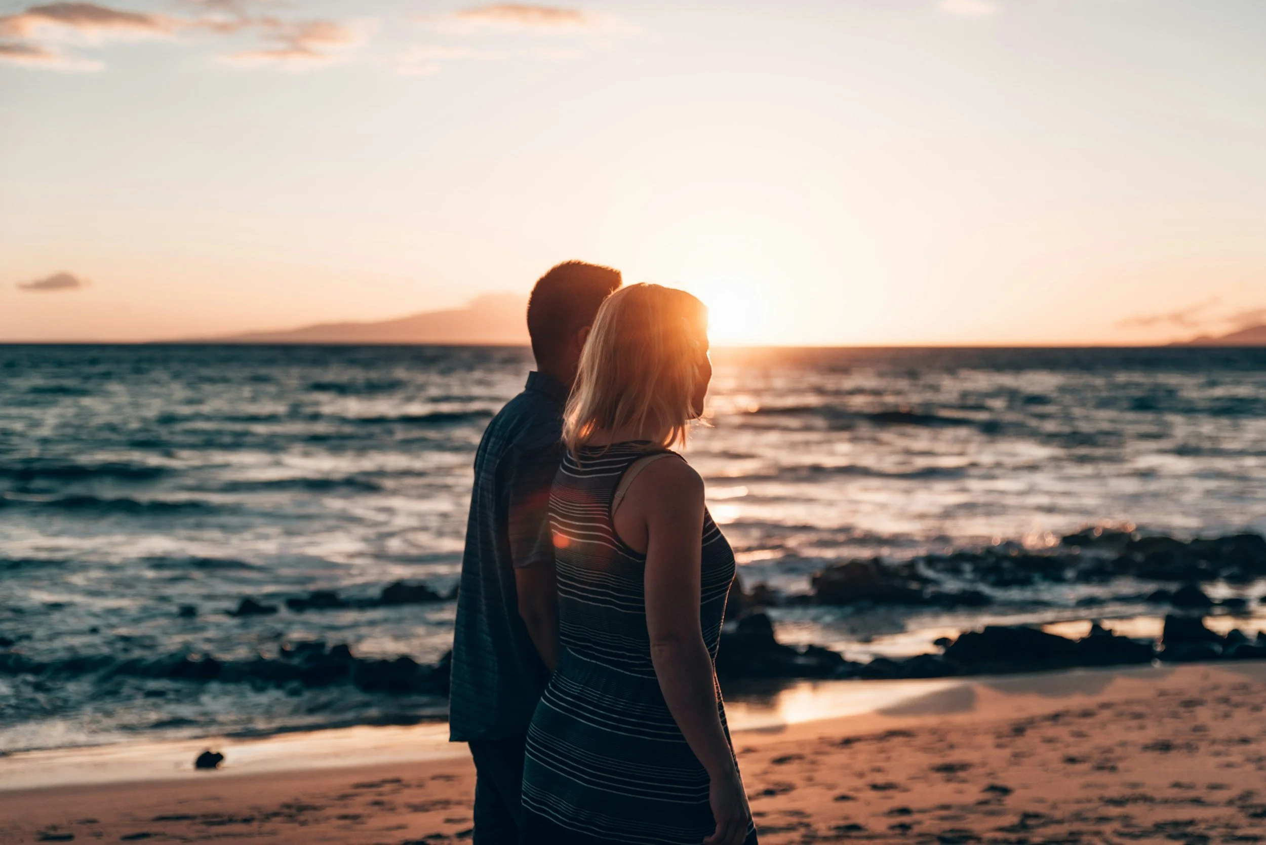 couple walking along a Kihei, Maui beach at sunset with ocean views