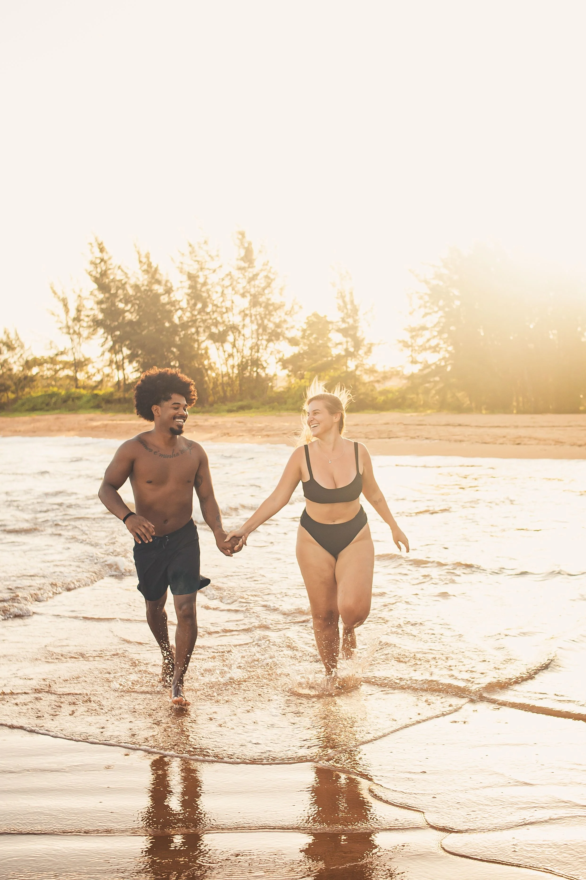 Couple running together along a beach at sunset