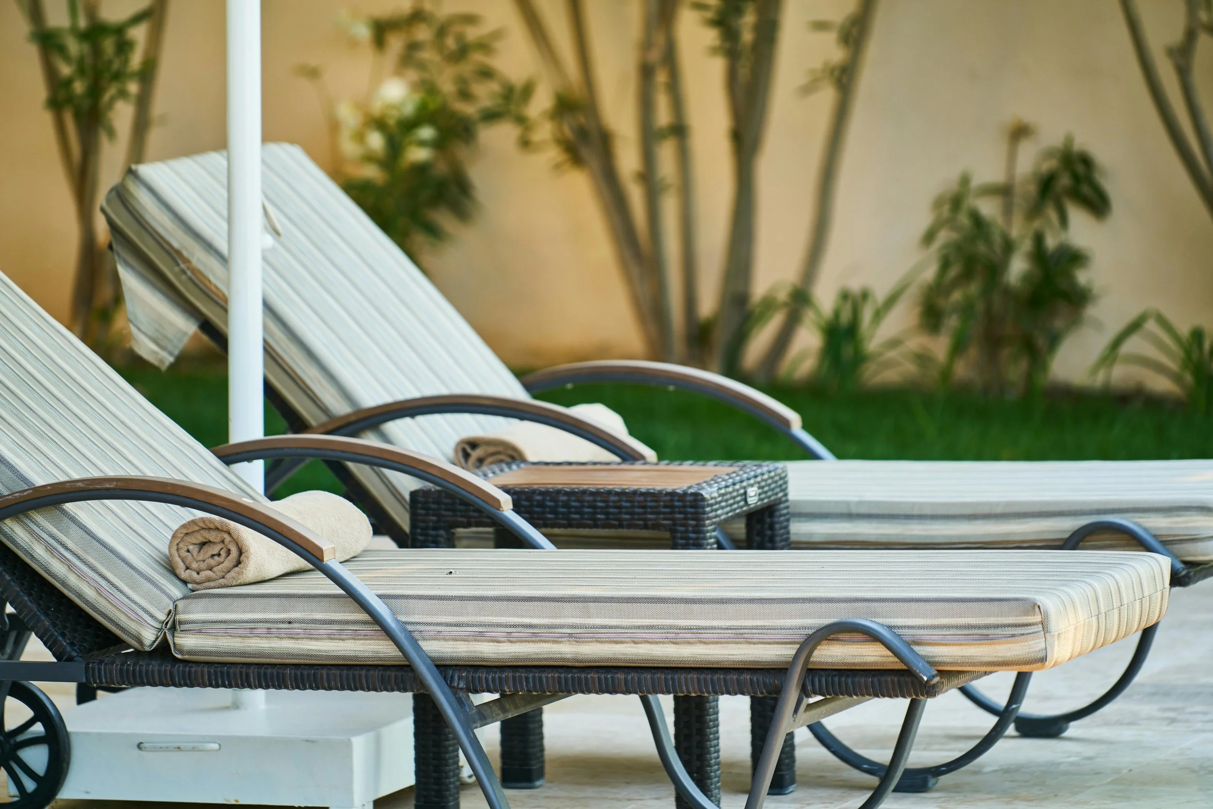 lounge chairs by a pool surrounded by tropical greenery