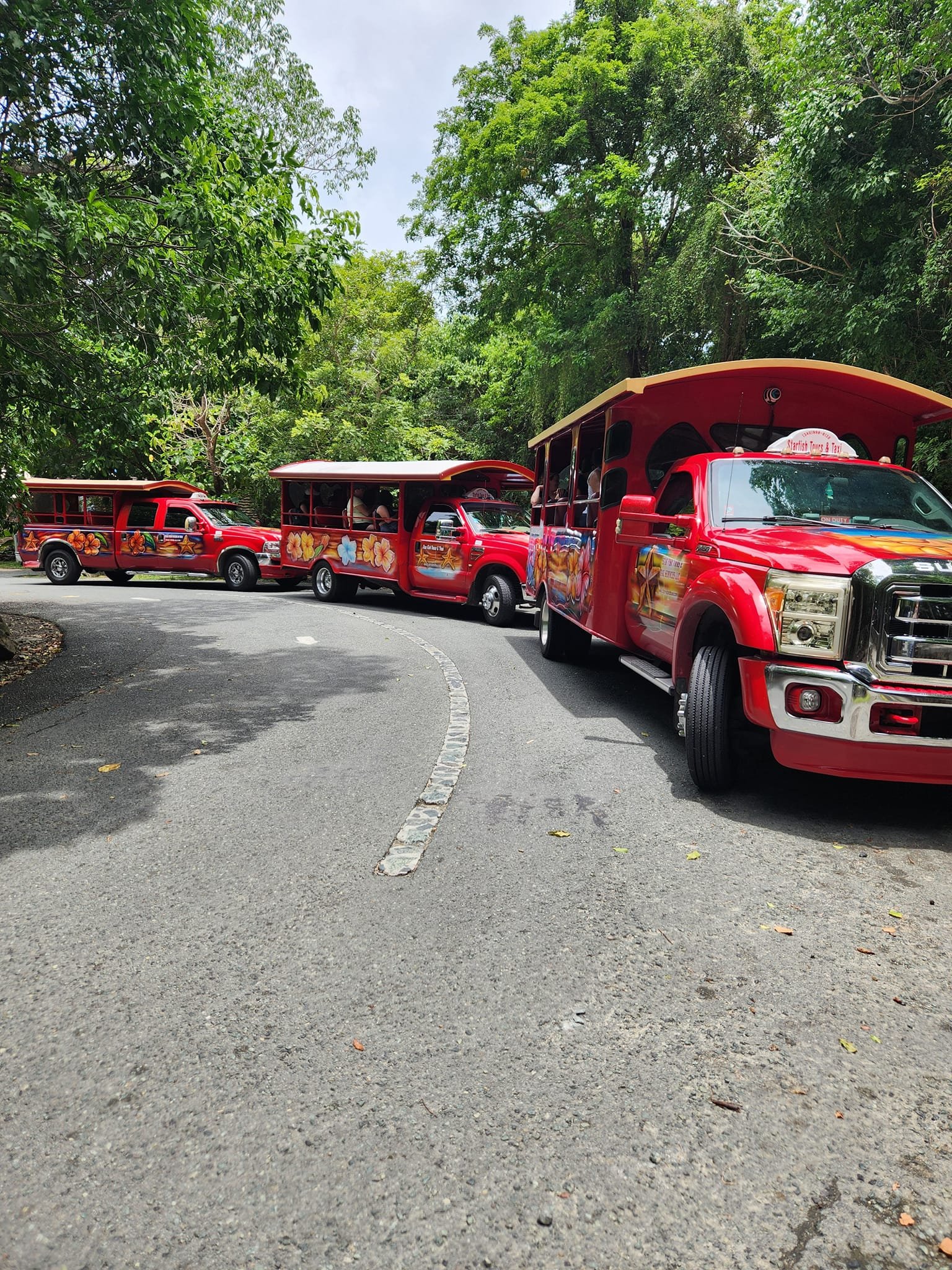 3 red busses with people having fun in them