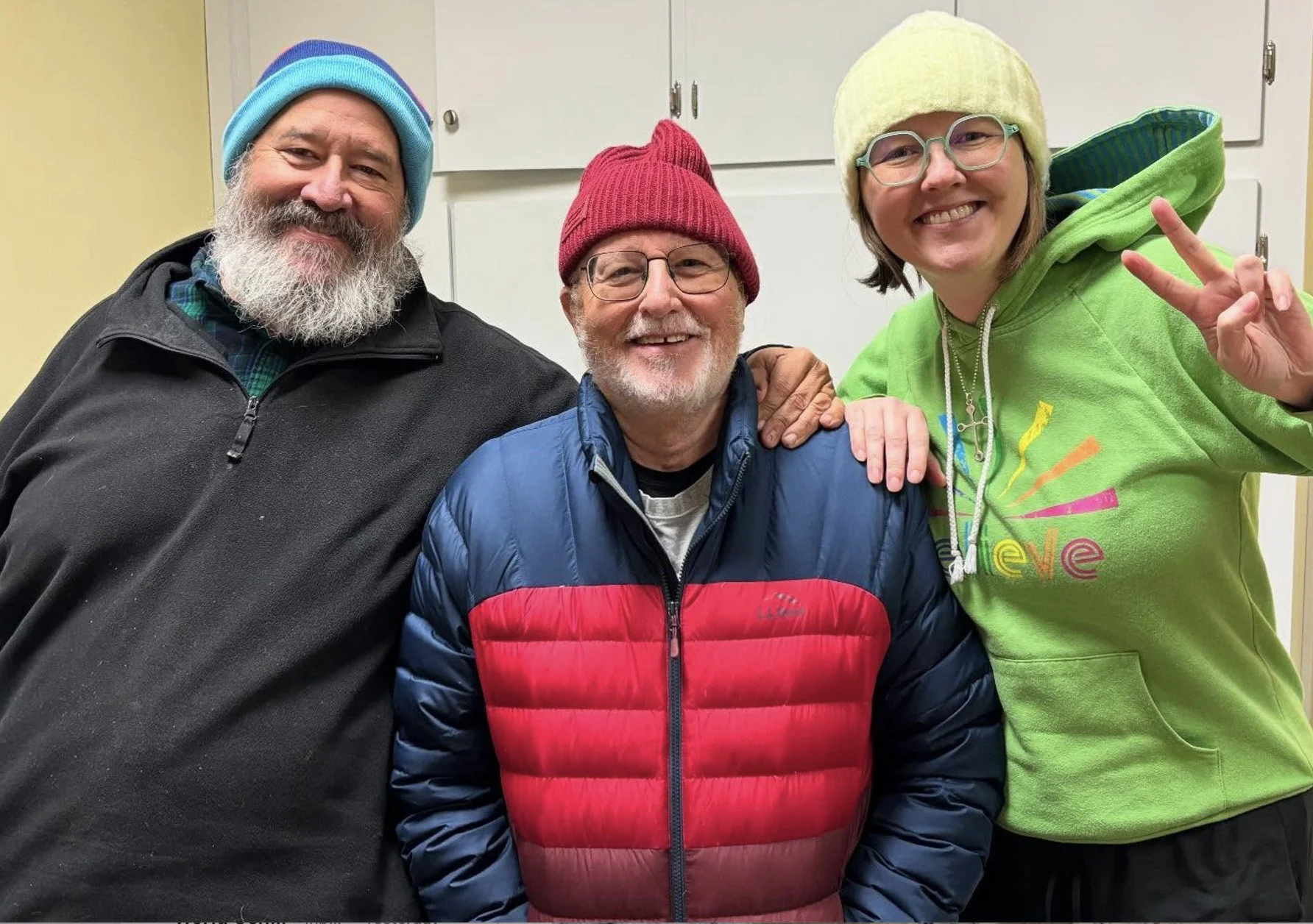 Three people smiling with Alissia in winter, in office