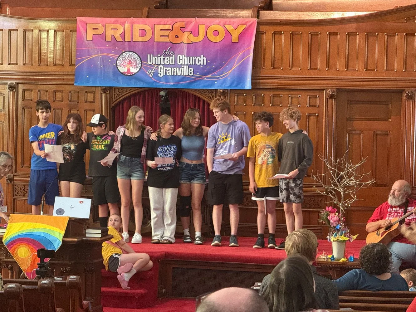 youth in front of pride and joy banner giving a presentation in church