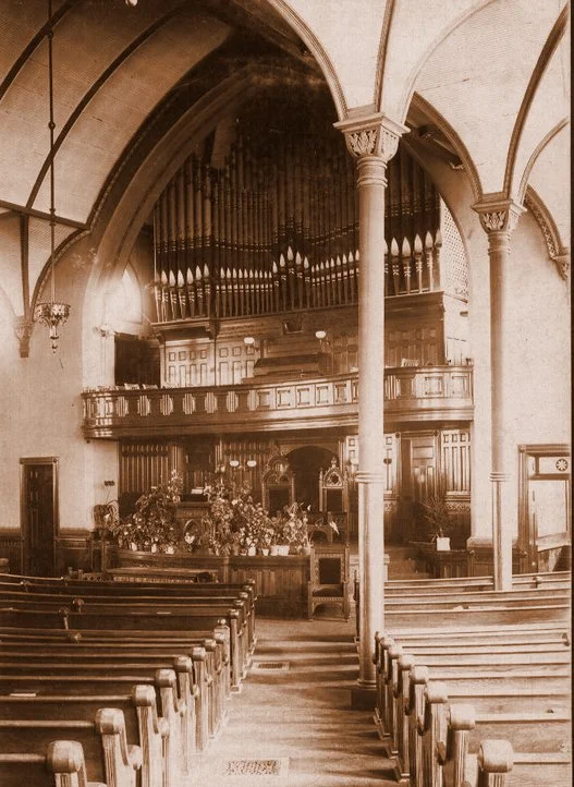 Sepia Oval image of our beautiful church from years ago with custom woodwork, columns, organ pipes and arches