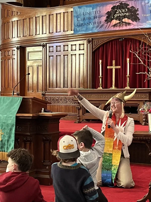 pastor alissia during children's chat with a viking helmet on holding a mic