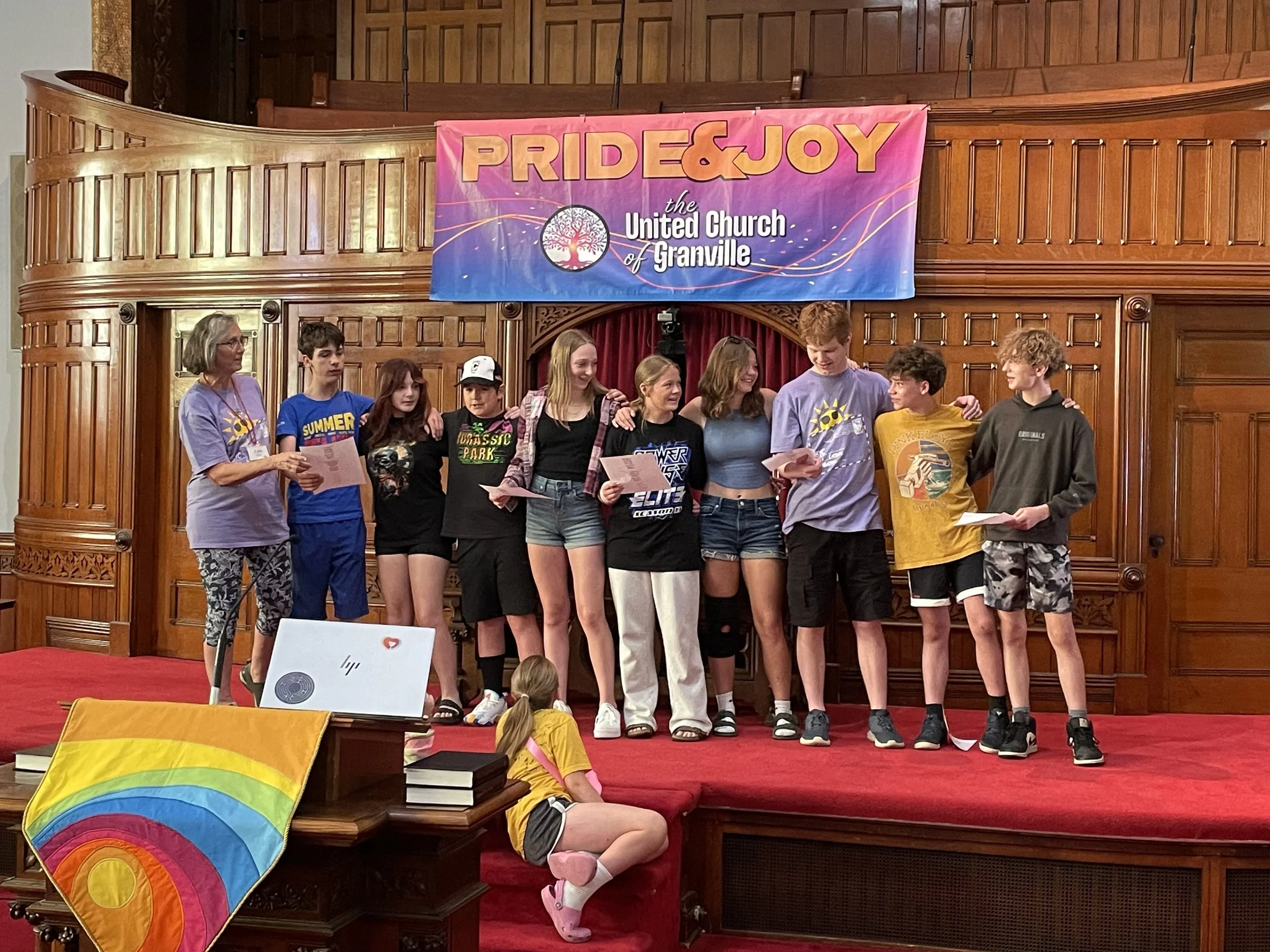 teens in front of worship presenting a report on beloved youth camp