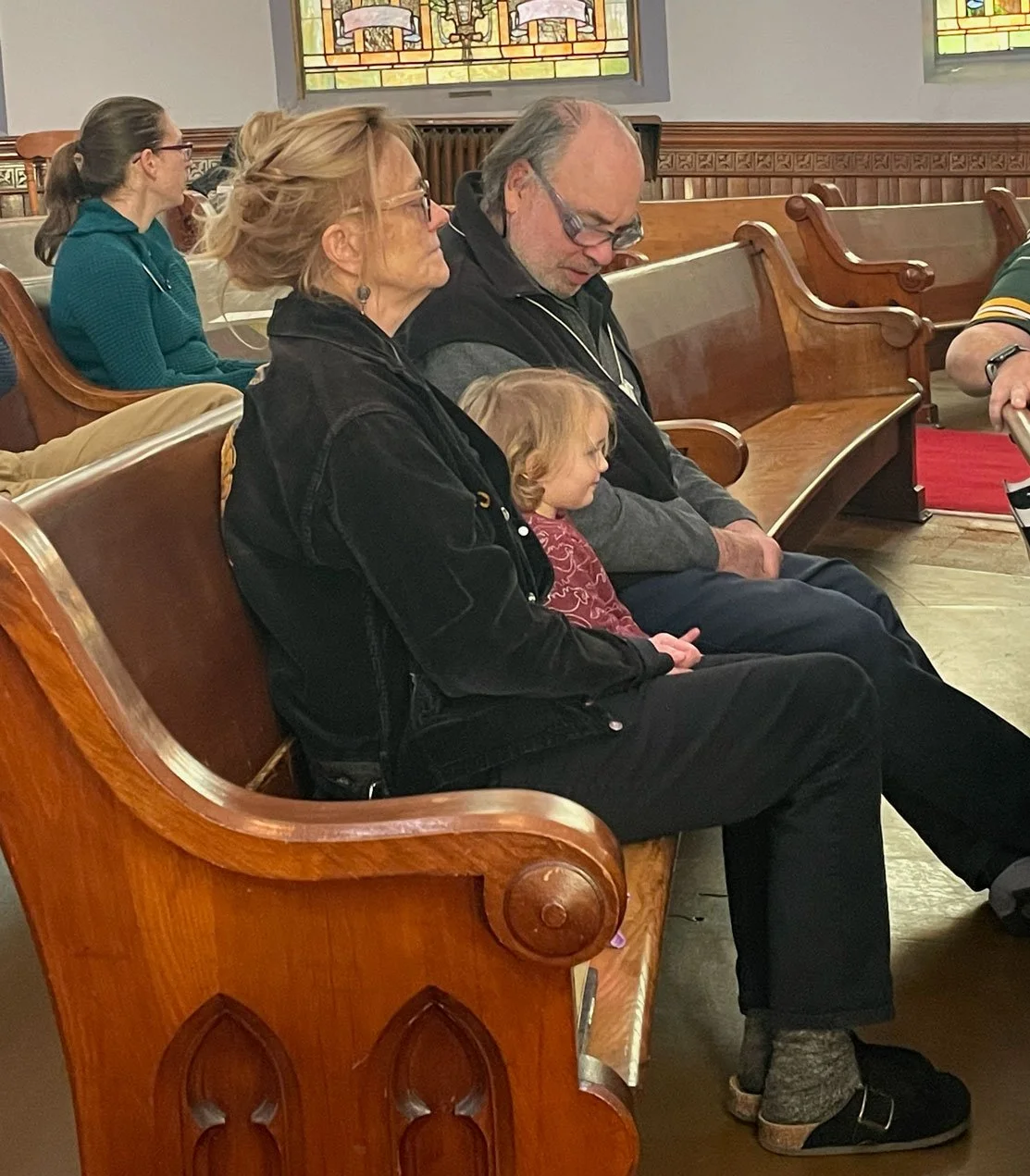 Two Adults and one child sitting in a pew during worship service