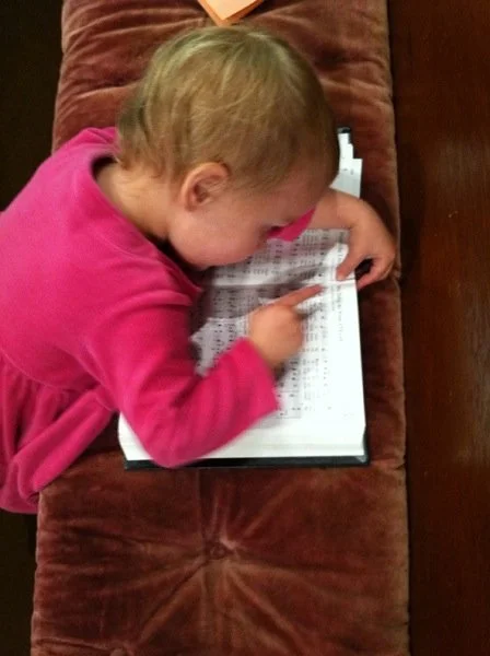 Baby pointing at hymns in hymnal as if she can read
