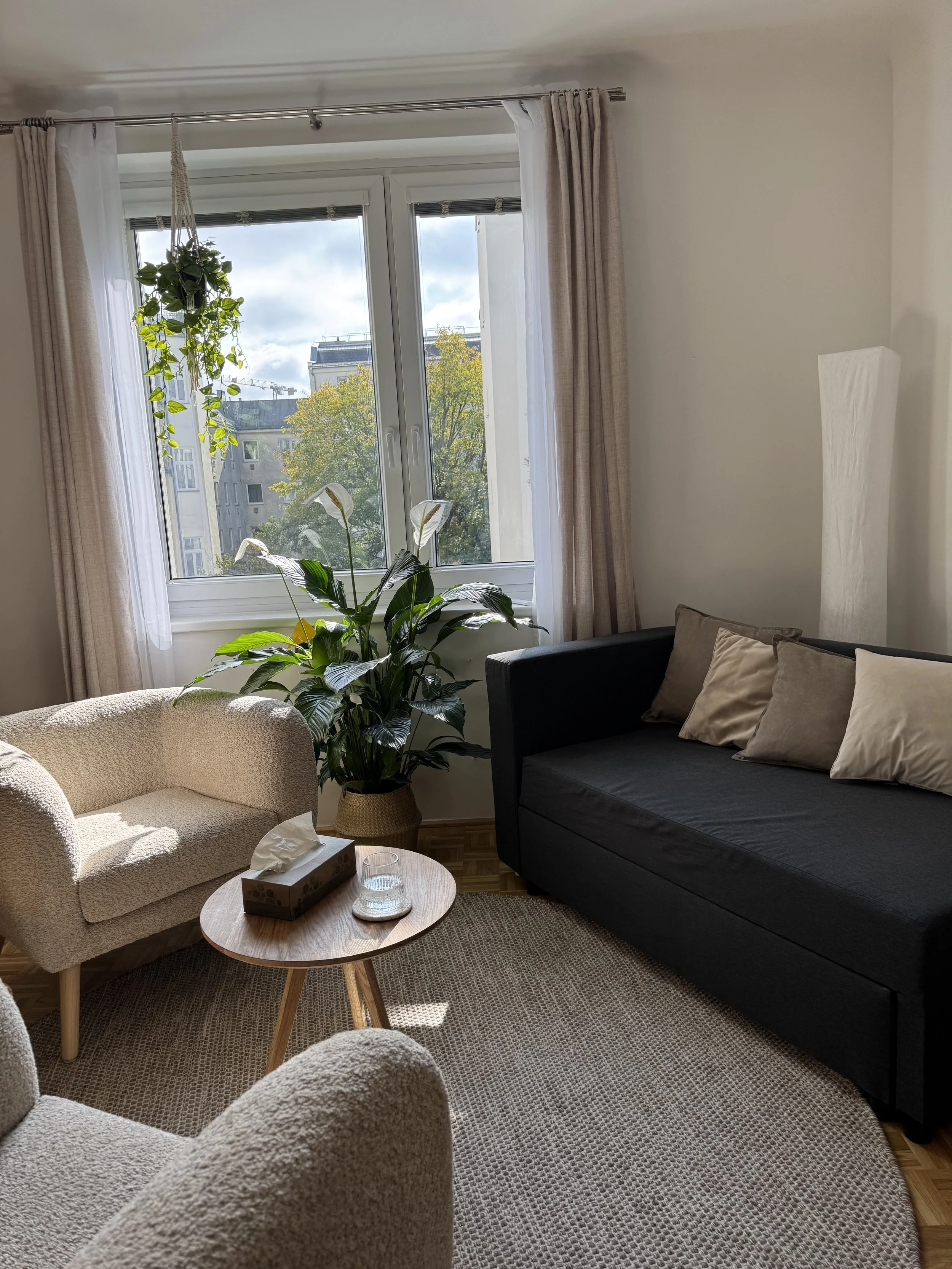 Praxisraum für Psychotherapie in 1190 Wien mit Sofa, großem Fenster und Pflanzen
