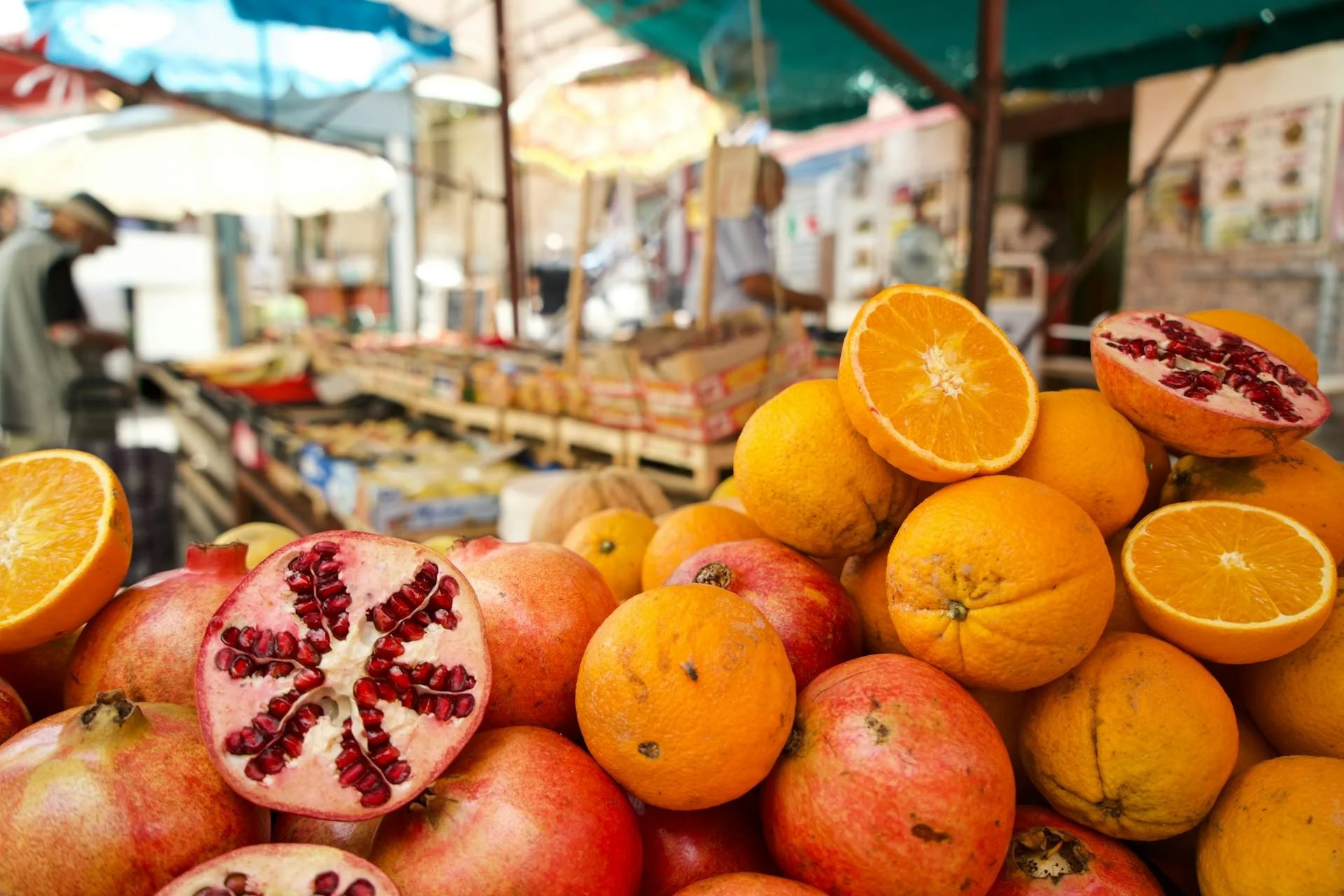 Fresh oranges and pomegranates displayed at a colorful outdoor market in Sicily