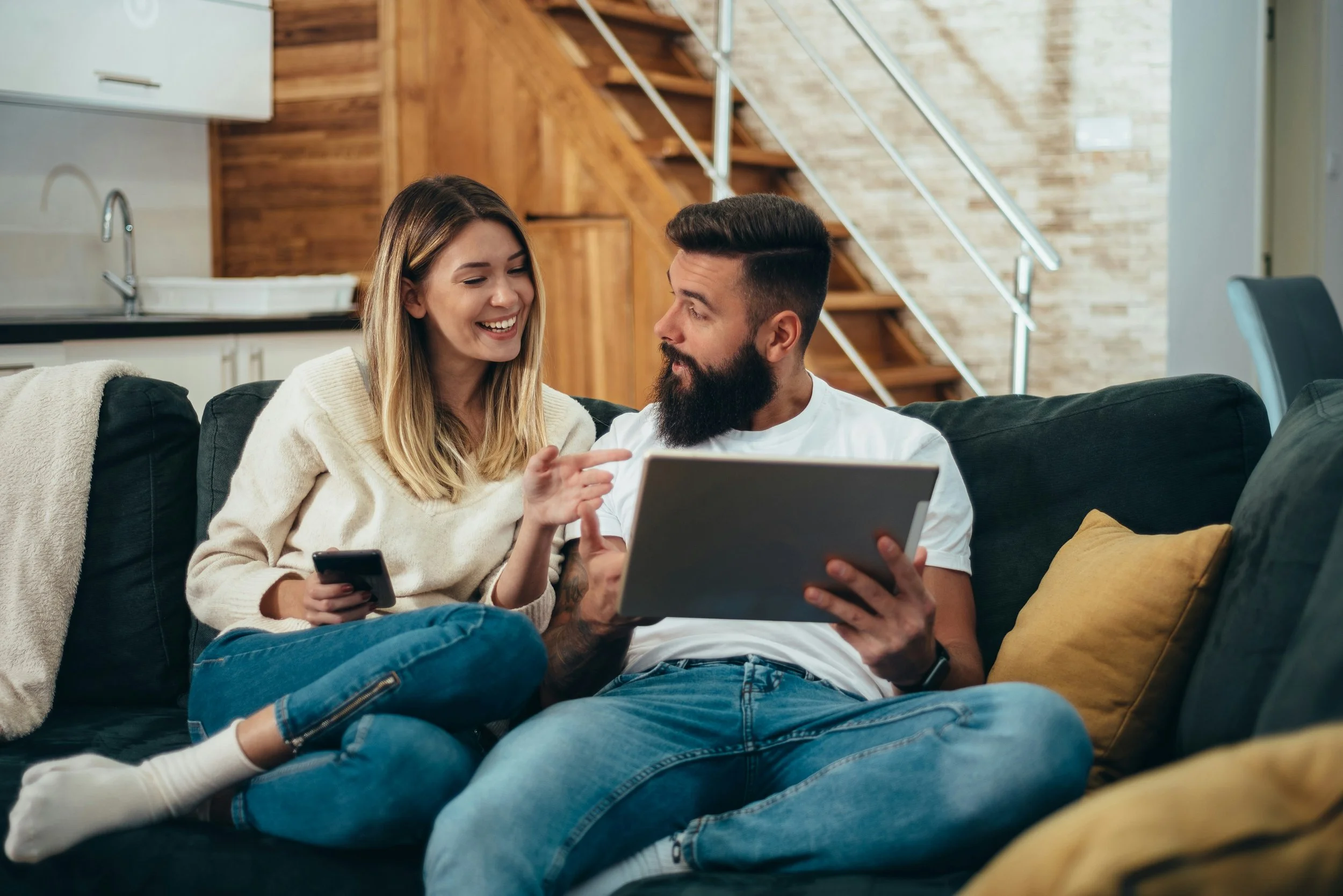 woman an man on couch looking at computer screen and smiling and talking
