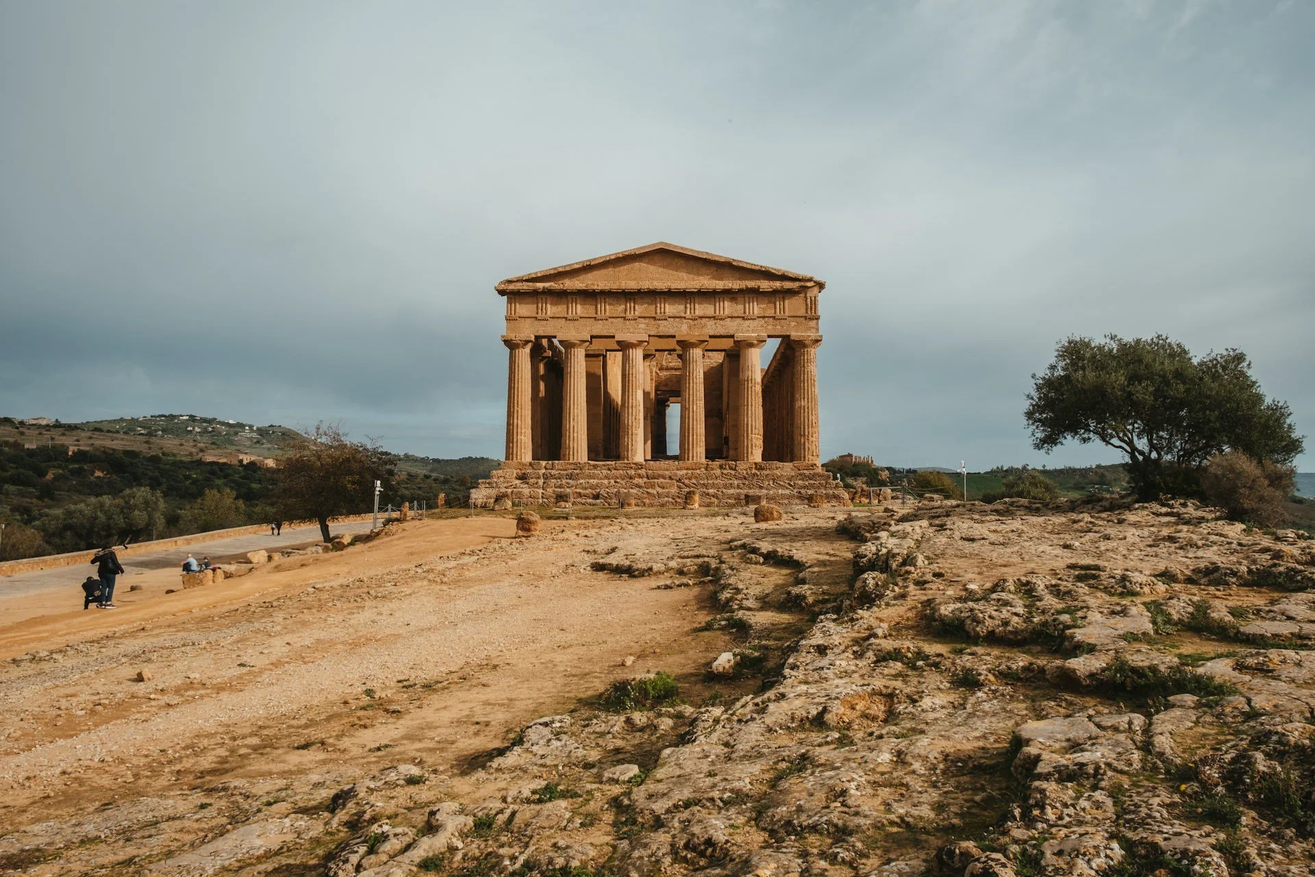 Ancient Greek temple in Sicily’s Valley of the Temples at golden hour with rocky landscape and olive trees.