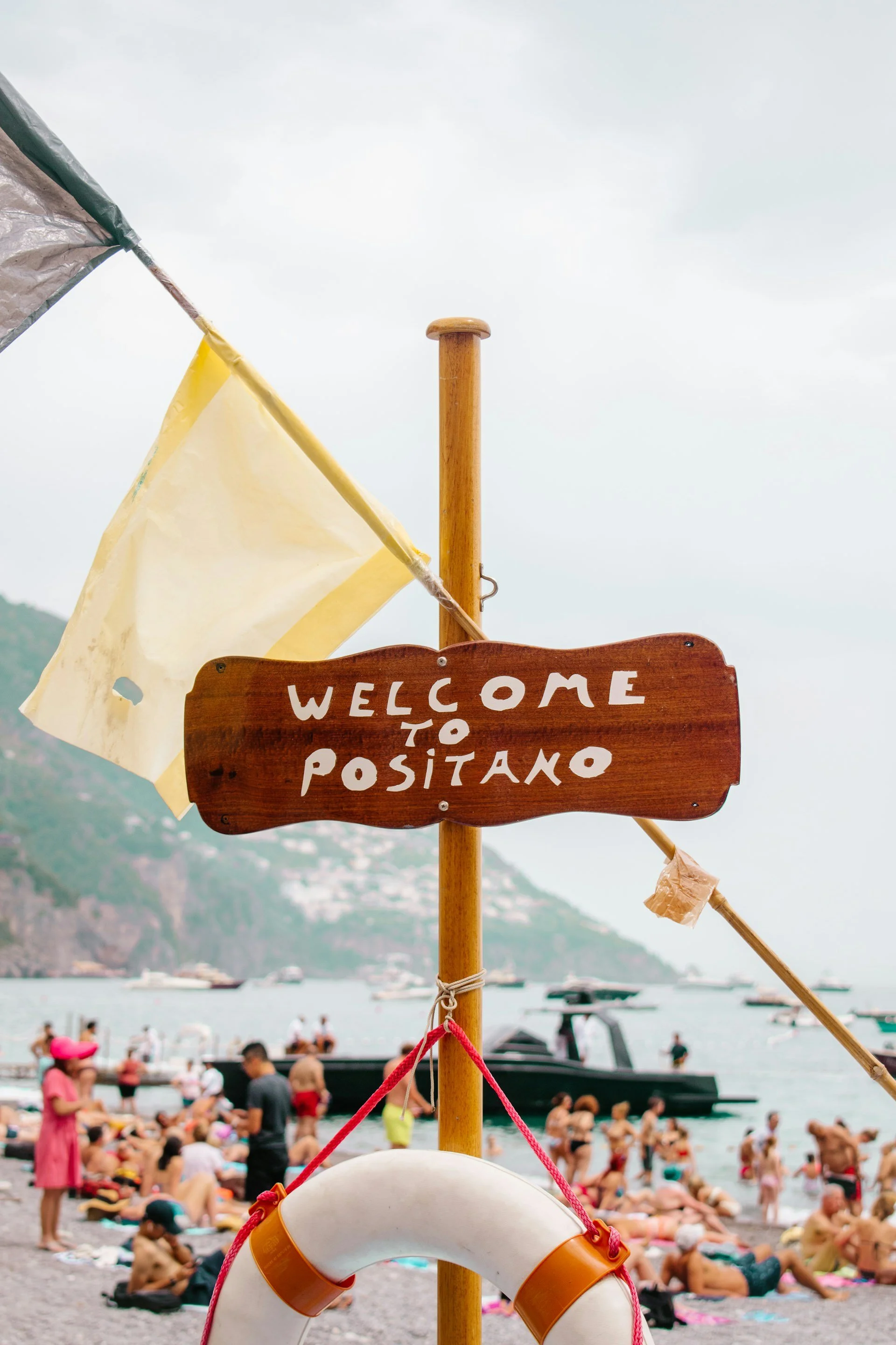 "welcome to positano" sign on beach in italy