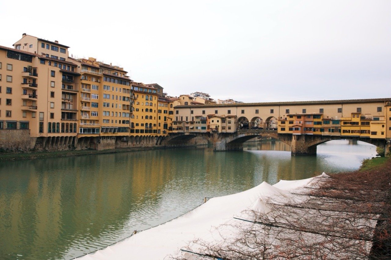 Historic Ponte Vecchio spanning the Arno River in Florence, Italy, lined with colorful buildings.