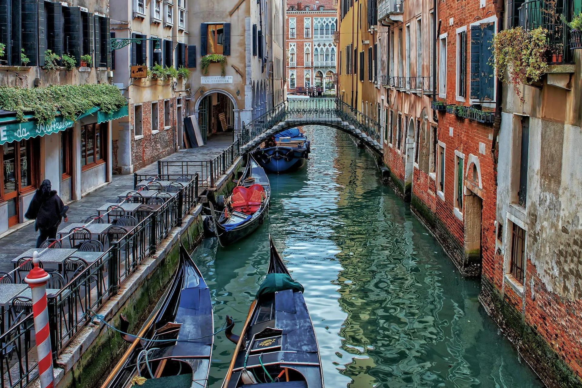 Gondolas along a quiet canal lined with historic buildings and a small bridge in Venice, Italy.