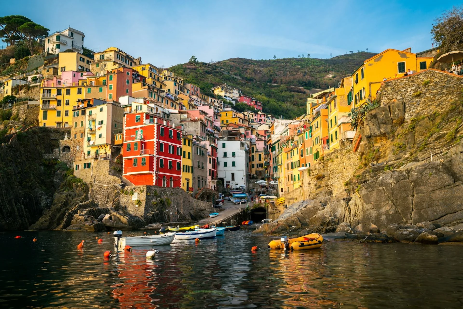 vibrant houses in Riomaggiore with small boats floating in a calm harbor surrounded by rocky cliffs