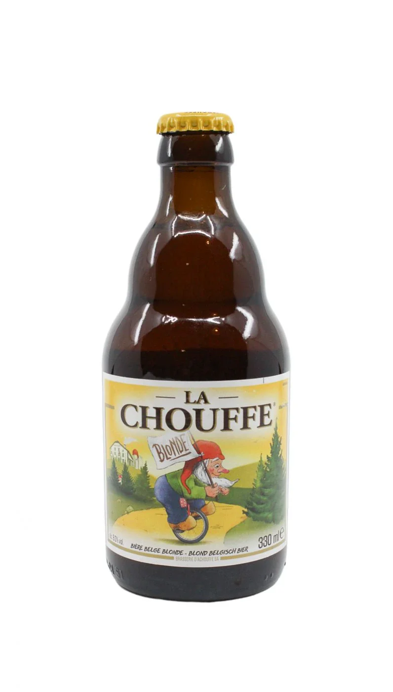 Brown glass beer bottle with a yellow cap and a label showing a cartoon gnome riding a unicycle, with trees and a house in the background, labeled "La Chouffe"