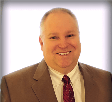 Headshot of a smiling man in a suit and tie against a white background.