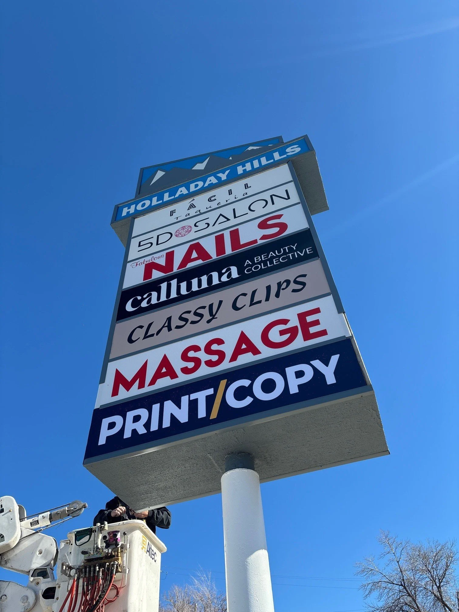Outdoor business pylon sign showing the different businesses in the shopping center including Print and copy Shop, Massage, Nails, Salon and Taqueria