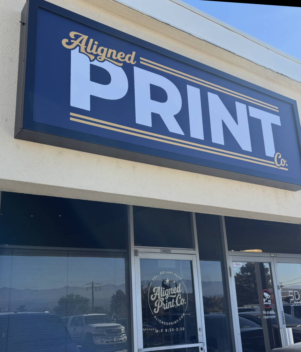Exterior of a print shop with a large sign reading 'Aligned Print Co.' in blue, white, and gold colors.