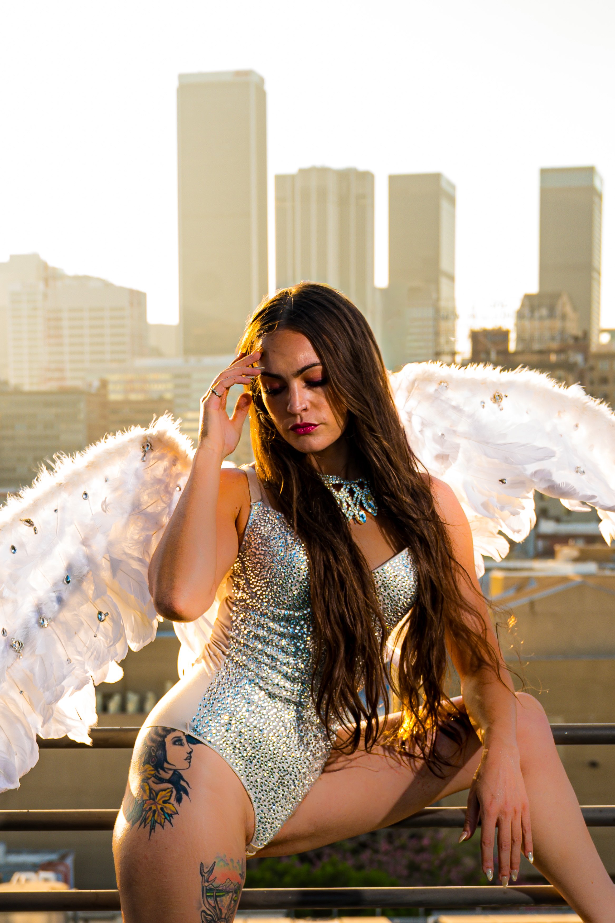 woman with angel wings , sparkling body suit with Los Angeles skyline in the background