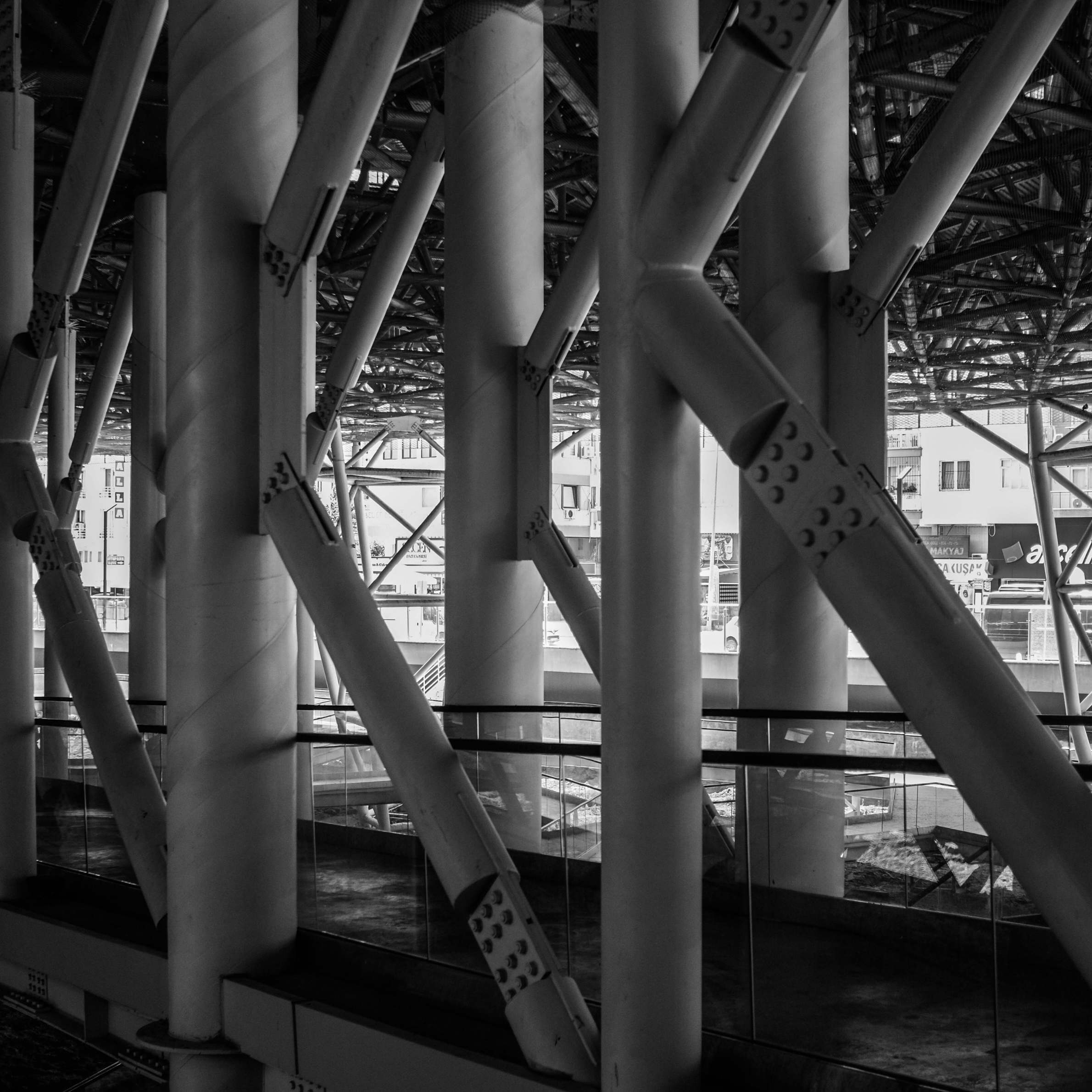 Black and white photo of an intricate structural framework with large vertical and diagonal beams, part of a modern architectural design inside a building.
