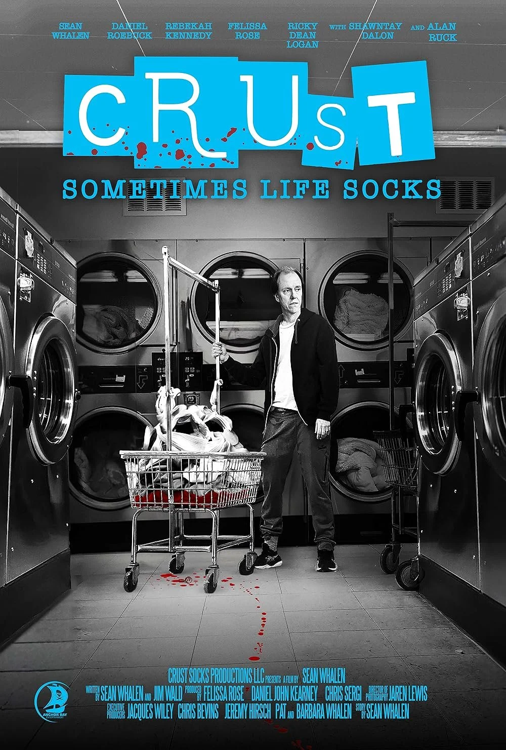 A man in a laundromat stands next to a shopping cart filled with laundry, surrounded by washing machines. The top of the image features the movie title 'CRUST' in bold blue letters with a subtitle 'Sometimes Life Socks.' In the background, part of the laundromat and washing machines are visible.