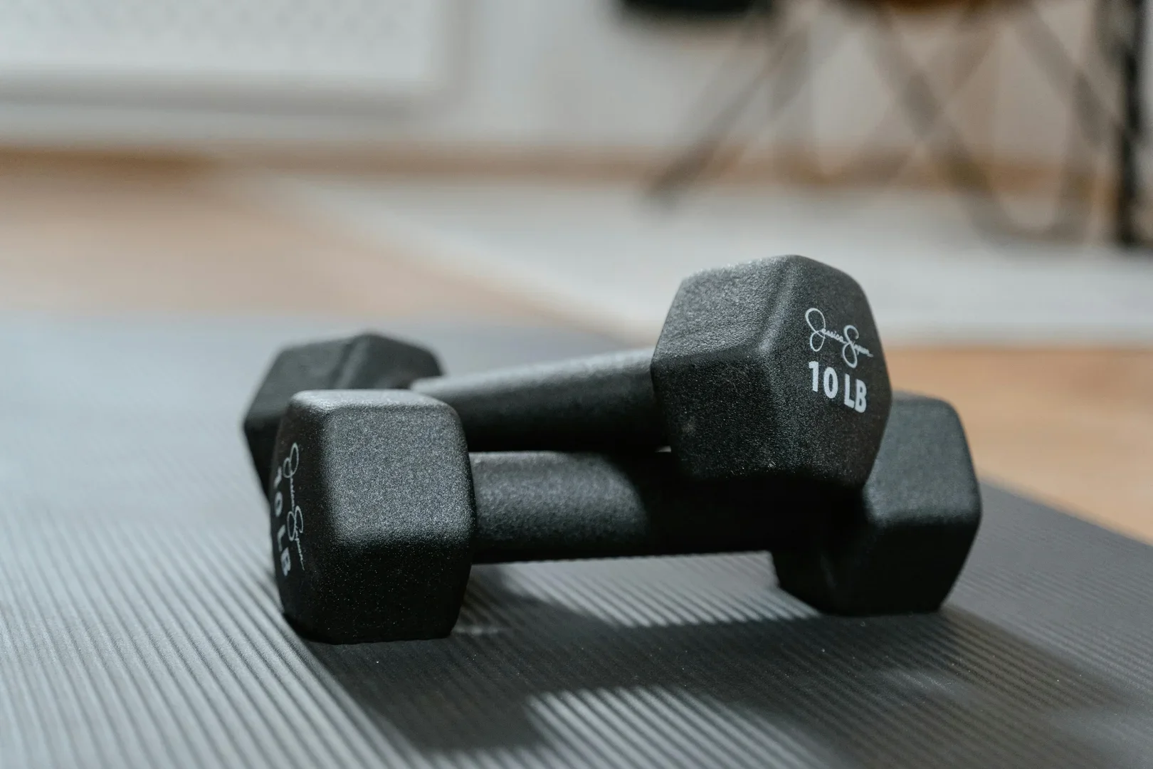 Pair of black 10-pound dumbbells resting on a textured exercise mat.