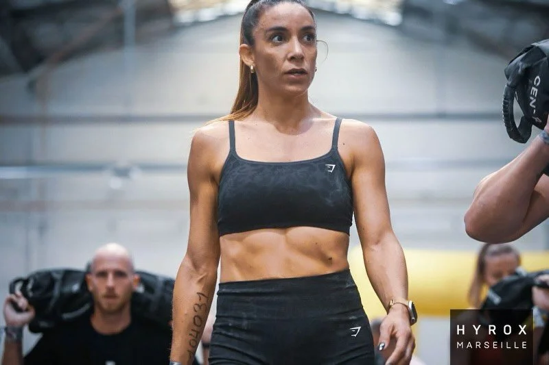 Une femme en tenue de sport représentant la détermination, avec d'autres personnes en arrière-plan.