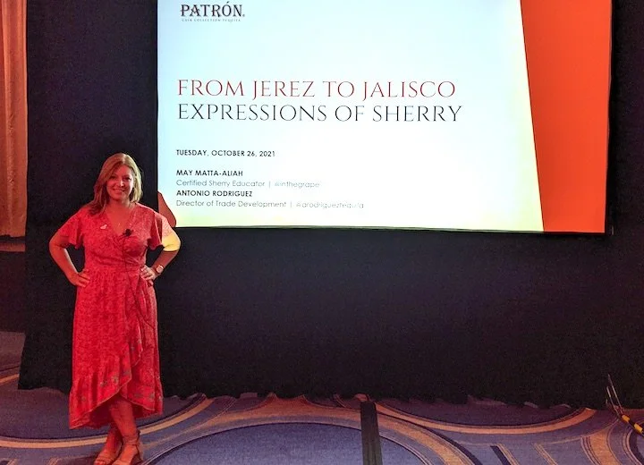 Woman in red dress standing in front of a presentation slide that reads "From Jerez to Jalisco: Expressions of Sherry" on October 26, 2021.