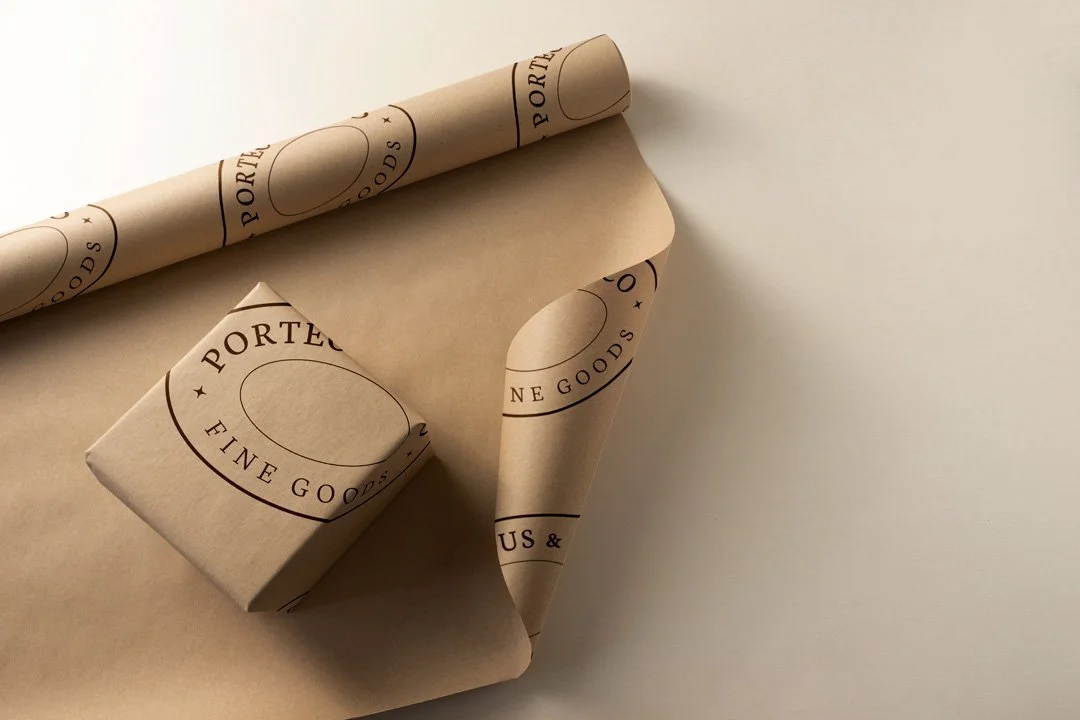 Brown wrapping paper and a small box with 'Porteous & Son Fine Goods' logo, partially unwrapped.