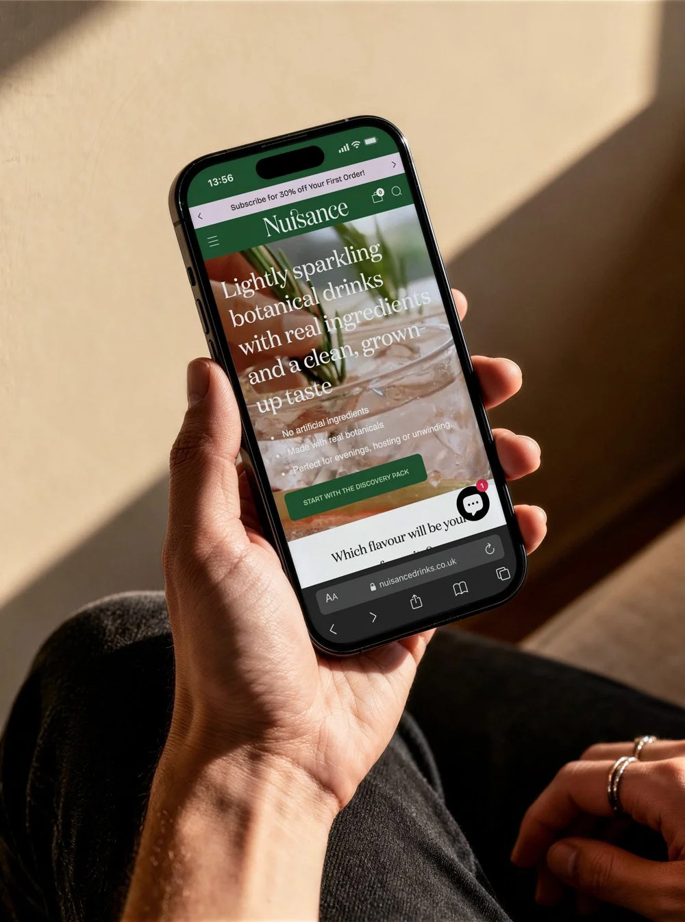 hand holding mobile phone showing nuisance drinks shopify website