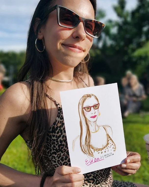 A lady wearing a leopard-print dress holds up a quick portrait by Siya Liu at a private event. 